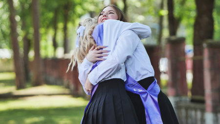 Two joyful female graduates hugging with sashes on their last day of school, commemorating their academic successの写真素材