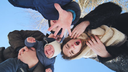 Joyful family playing outside during sunny winter day, laughing and creating playful memories togetherの写真素材