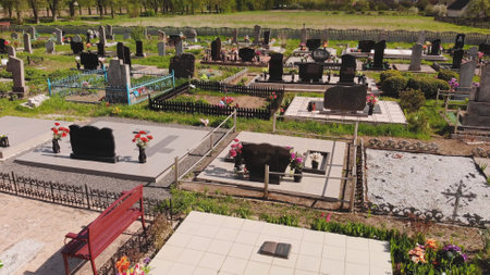 Weathered tombstones resting among cemetery fences, decorated with memorial flowers, symbolizing quiet reverence and lossの写真素材
