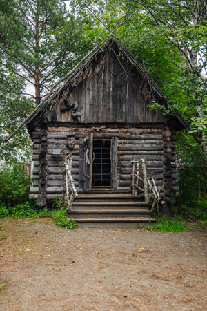 Weathered wooden hut with barred entrance standing among dense forest trees, embodying haunting russian folklore atmosphereの写真素材