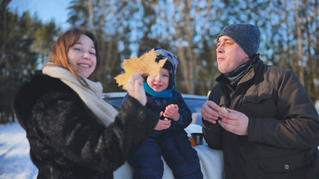 Winter forest picnic with family, laughing and sharing warm meal amid snow covered trees, bonding through joyful shared momentの写真素材