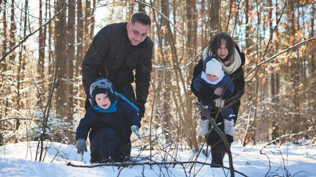 Family enjoying winter landscape, walking together through snow covered forest, sharing warmth and...