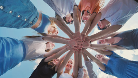 School friends come together in a circle, joining hands to represent unity, teamwork, and collaborationの写真素材