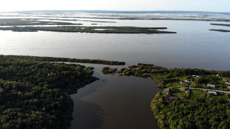 Nature on the Amur River in Russia. Aerial perspective capturing green river islands merging, winding waters surrounding peaceful riverbank settlement amid verdant landscapeの写真素材