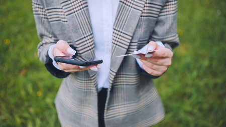 Businesswoman holding credit card and using smartphone for online shopping in a green park
