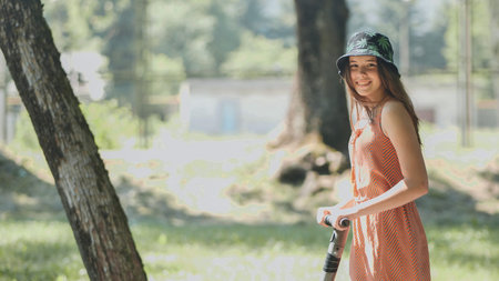 Happy teenager riding electric scooter in a park during summer, enjoying sustainable transportation...
