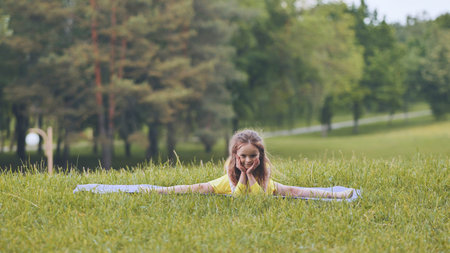 Flexible girl practicing gymnastic exercises outdoors, promoting healthy lifestyle and childrens...