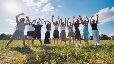 High school students happily leaping in a field, celebrating their summer break with raised arms