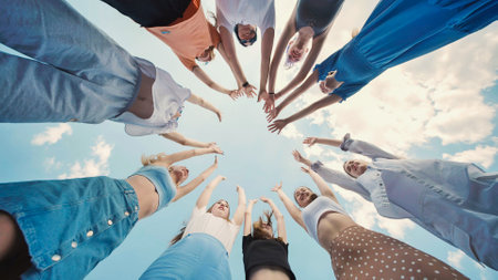 School friends joining hands in a circle, raising arms in celebration of their unity and friendshipの写真素材