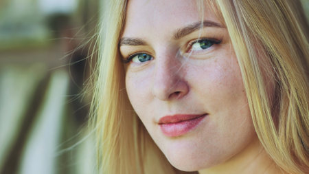 Blonde woman with freckles sharing warm smile, radiating confidence and natural beauty against soft backgroundの写真素材