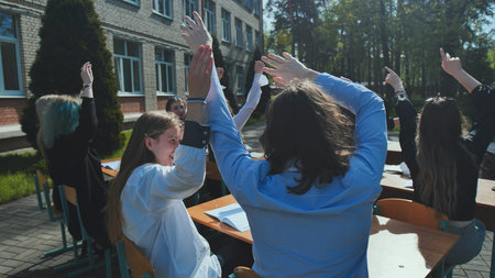 Happy students raising hands outdoors, celebrating the end of the school day, enjoying freedom and...