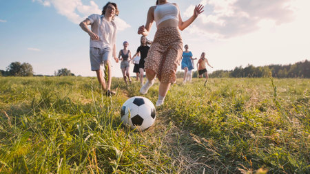 Group of young students playing soccer in a meadow at sunset, enjoying their free time togetherの写真素材