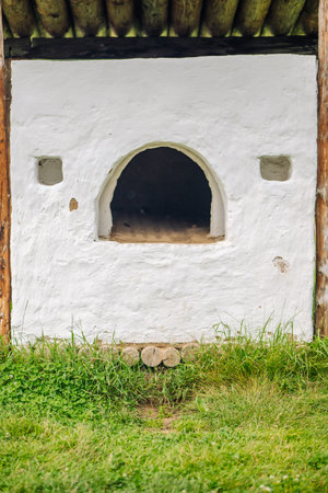 Whitewashed outdoor stove with wooden roofing in a grassy area, showcasing traditional russian constructionの写真素材