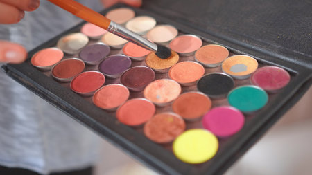 Makeup artist holds shadows in his hand and paints a model.の写真素材