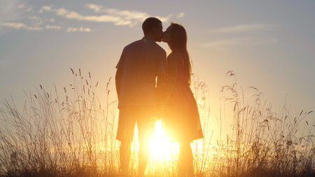 Silhouettes of happy lovers kissing at sunset.の写真素材