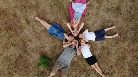 Happy family lies on the grass in the form of sun rays.の写真素材