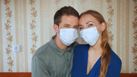 Home quarantine concept. Spouses kiss at home in a mask.