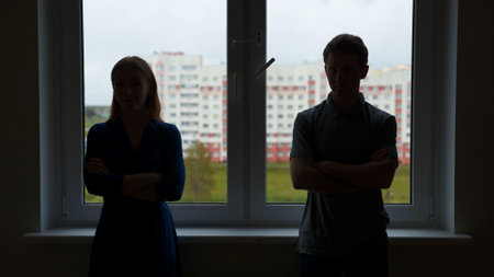 Silhouettes of young spouses against the backdrop of a window in a quarrel.の写真素材