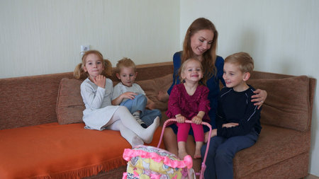 Happy mother of many children with her children on the couch in the house.