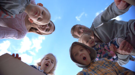 Happy young family opens the box with gifts on a background of blue sky.の写真素材