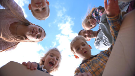 Happy young family with children opens the box and rejoices against the blue sky.