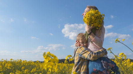 A loving son hugs his mother in a rapeseed field.