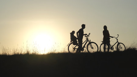 Friendly family with a child on bicycles during sunset.の写真素材