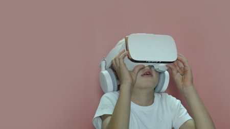 A little boy is watching a video in virtual glasses on a pink background.の写真素材