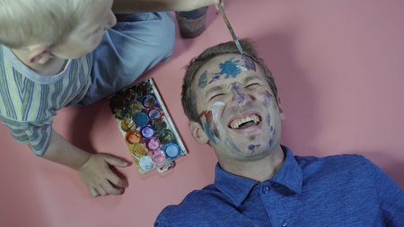 A cheerful father allows his child to paint the face.の写真素材