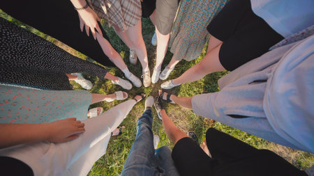 Group of high school students forming a circle on grass, showing unity and friendship during summerの写真素材
