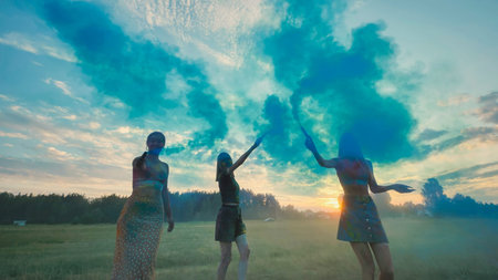 Three school friends having a lively celebration, holding up colorful smoke bombs against a stunning...