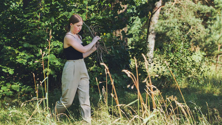 A young woman carrying branches for the fire.