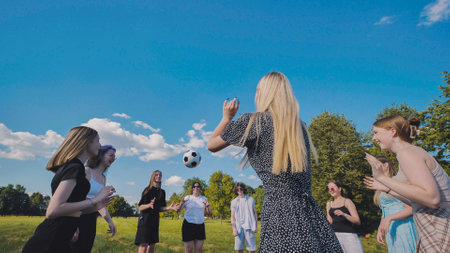 Friends toss a ball to each other in a meadow on a summer day.の写真素材