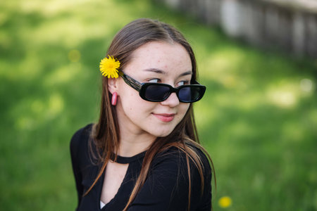 Teenage student with dandelion in hair and sunglassesの写真素材