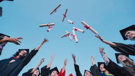 Students in graduation attire tossing their diplomas in the air, rejoicing in their academic successの写真素材