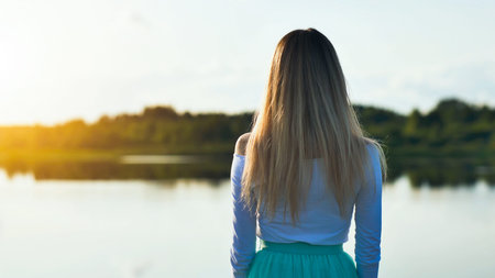 Blonde woman relaxing lakeside during golden sunset, basking in serene natural landscape