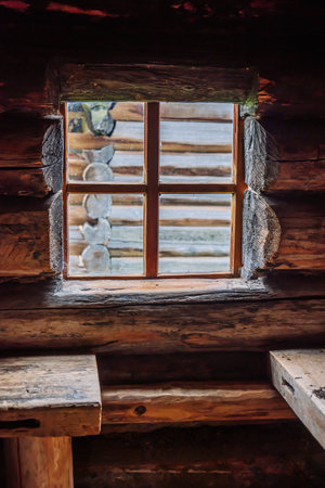 Weathered wooden window framing thick log walls, revealing traditional russian cabin construction with authentic handcrafted carpentry detailの写真素材