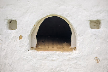 Whitewashed traditional russian stove with large arching entrance and small square openings, representing historic culinary practicesの写真素材