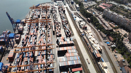Aerial view of a bustling industrial port, featuring cargo cranes loading and unloading containers...