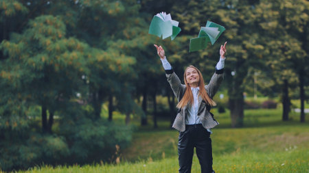A young schoolgirl tosses up her notebooks.の写真素材