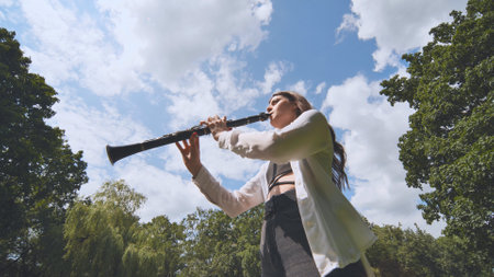 Girl plays clarinet against sky.の写真素材