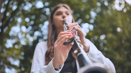 A girl plays the clarinet in the park in the summer.の写真素材