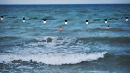 String of lights illuminating the beach of Crimea with tourists swimming in the seaの写真素材