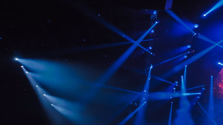 Blue stage lights illuminating dark concert hall during music festivalの写真素材
