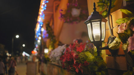 Warm street lamp illuminates flowers adorning a building in crimea at night, creating a cozy atmosphereの写真素材