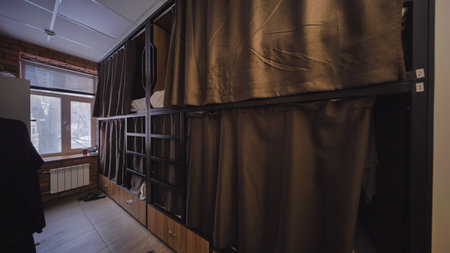 Hostel room with brown curtains providing privacy in capsule beds