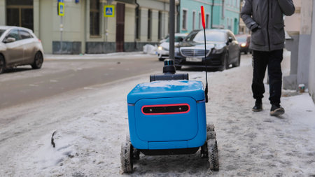 Autonomous delivery robot moving on a snowy sidewalk in Moscow.の写真素材