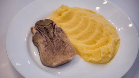 Boiled beef tongue served with mashed potatoes on white plateの写真素材