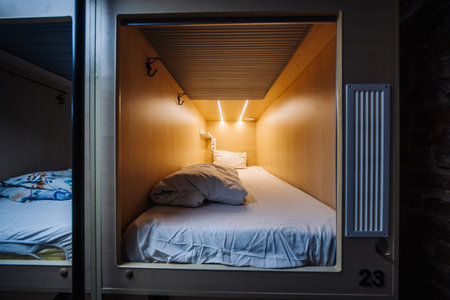 Capsule hotel room number twenty-three featuring comfortable bed, blanket and pillowの写真素材