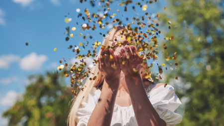 The girl blows a golden confetti out of her hands.の写真素材